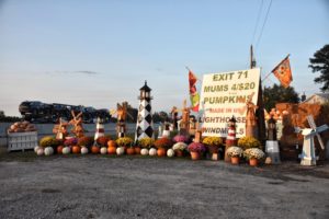 A display of pumpkins, mums, lighthouses, and windmills in an entranceway.